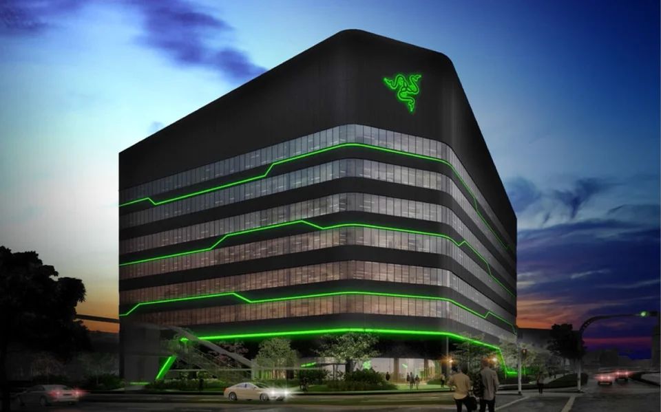 Photograph of the headquarters of Razer, the world's leading lifestyle brand for gamers, in Singapore. The black, architecturally striking building features green light strips and the brand's iconic snake logo.