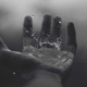 Image of waterdrops falling onto an outstretched hand.