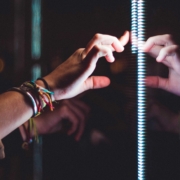 The image shows a hand in the dark touching a bright reflective surface with a strip of glowing LEDs.