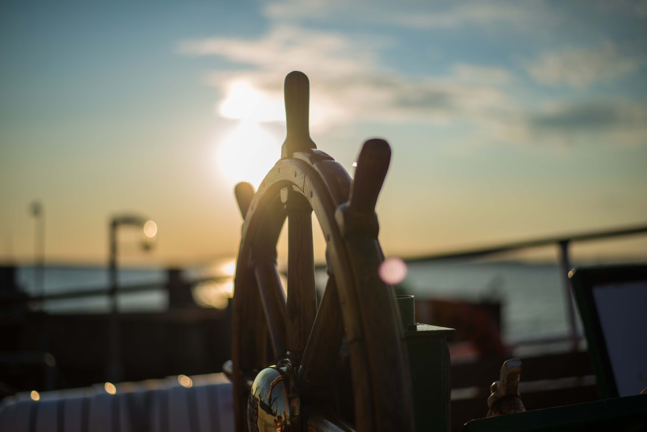 A wooden ship's wheel in the sunset.